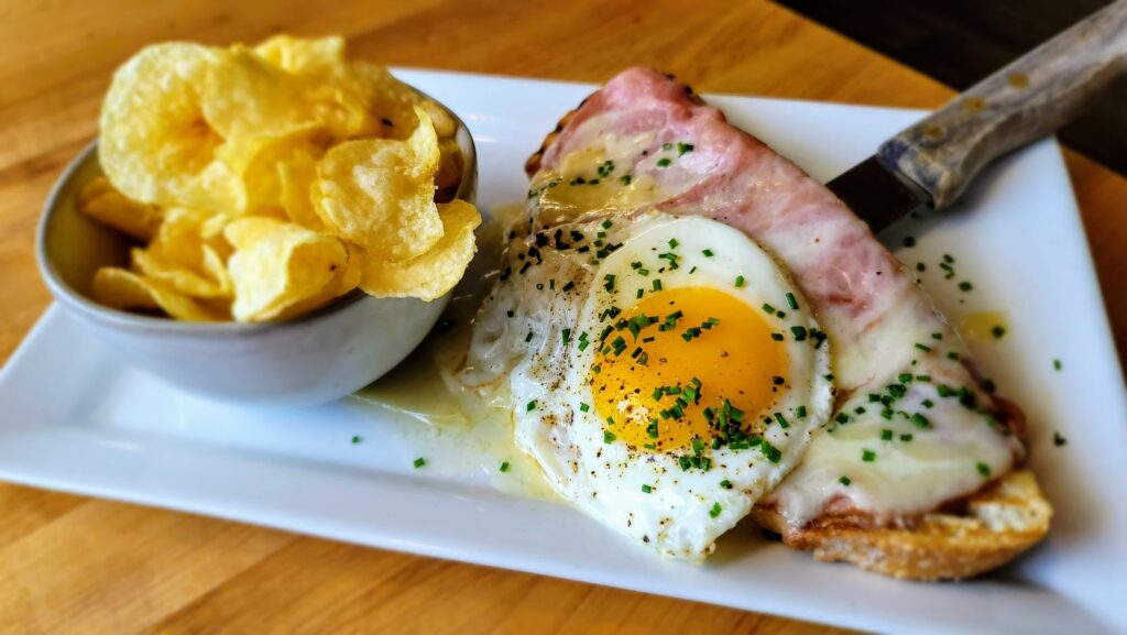 Le Croque Monsieur - Open-faced, dijonnaise, shaved ham, bechamel, melted Gruyere, topped with a sunny side-up egg.