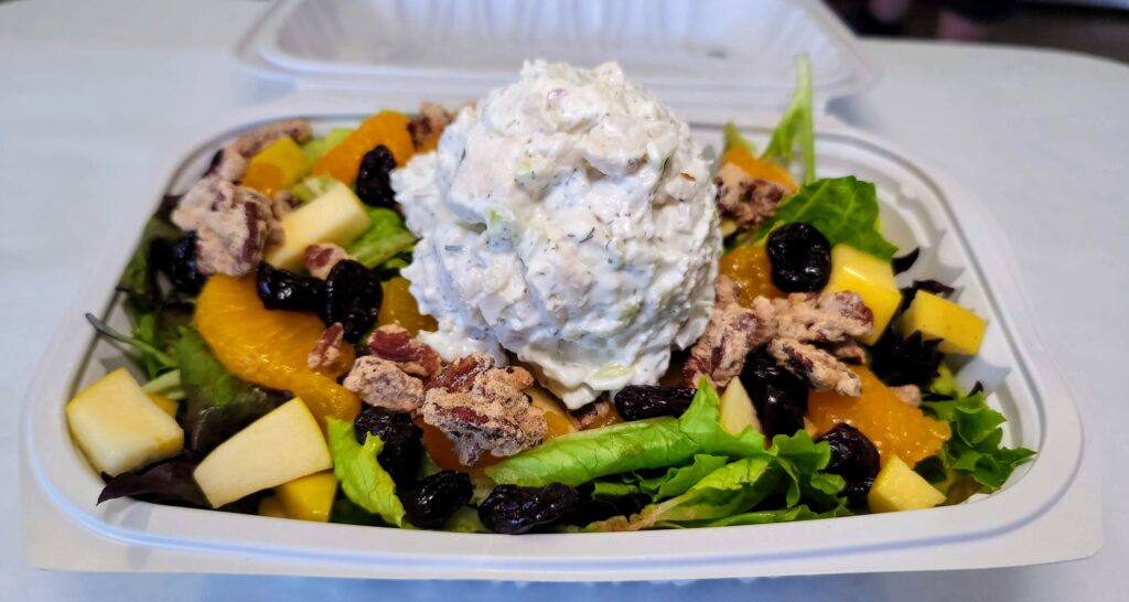 Fruit & Nut Salad Plate - Fresh blend of artisan lettuce, with a scoop of chicken salad, fresh apples, mandarin oranges, sprinkled with dried cherries & candied pecans from Cravings in Vero Beach Florida
