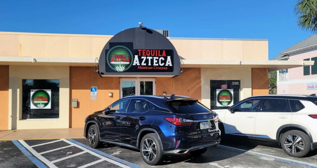 Tequila Azteca" is located in Vero Beach, Florida, in the Miracle Mile shopping area. The front of the building features a cream trim, orange walls, and an arched sign above the door in black, green, red, and white.