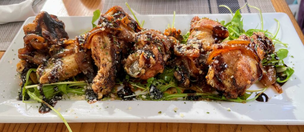 A plate of crispy and succulent chicken wings with a savory caramelized onion topping, perfect for snacking or as a side dish