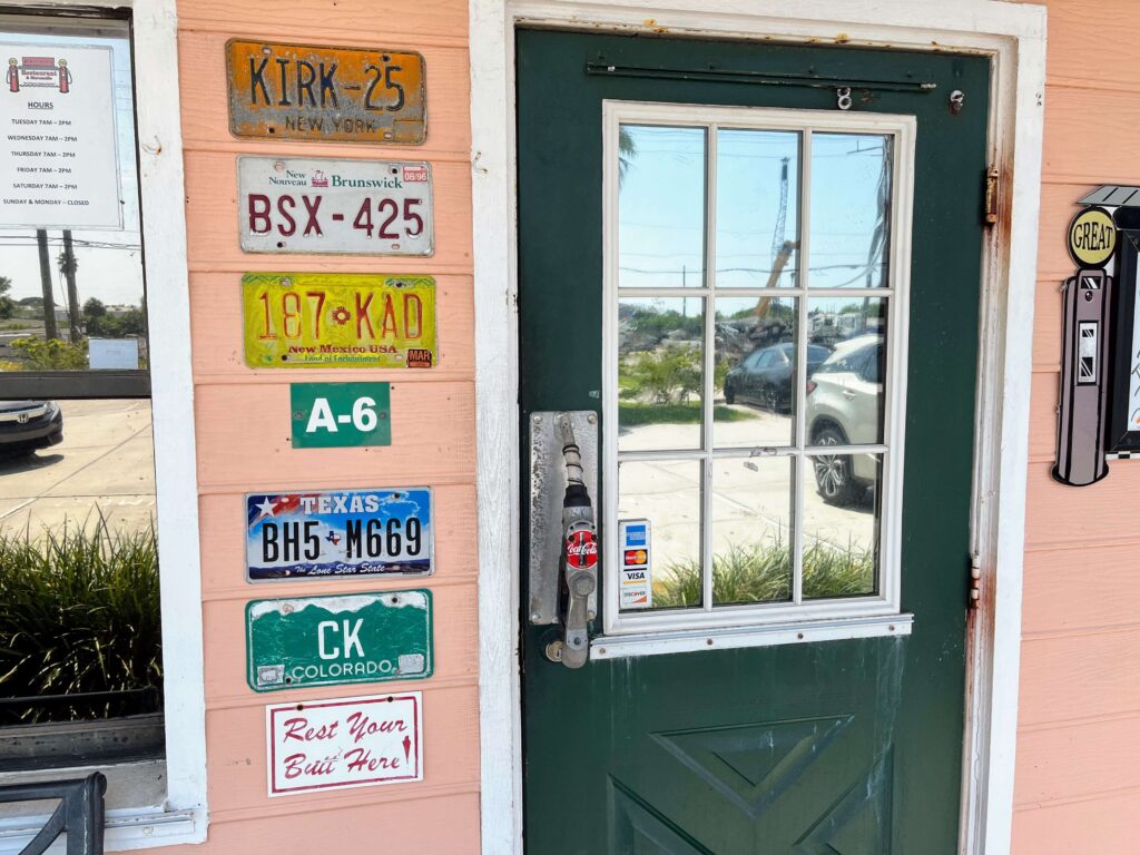 Front door entrance decorated with license plates and a gas pump pull handle from Mrs Mac's Fillin Station restaurant located in Vero Beach Florida