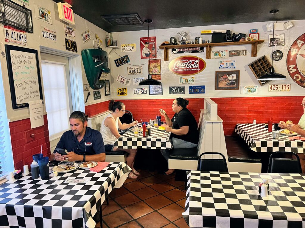 Inside dining room decorated with checkerboard table cloths, red and white on the walls, and vintage decorations on the wall at Mrs Mac's Fillin Station restaurant located in Vero Beach Florida