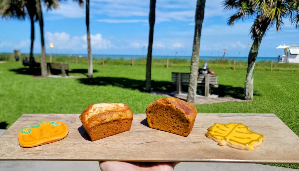 a photo of fall treats as prepared by Cravings located in vero beach florida on a board displayed at Humiston Park with an ocean view in the background.
