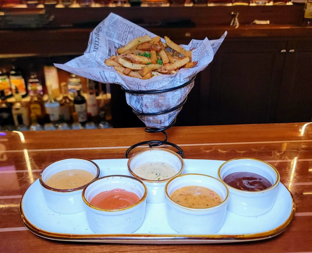 Pomme Frites served in a cone shaped basket with a variety of dipping sauces as prepared by Stringers Tavern & Oyster Bar in stuart florida
