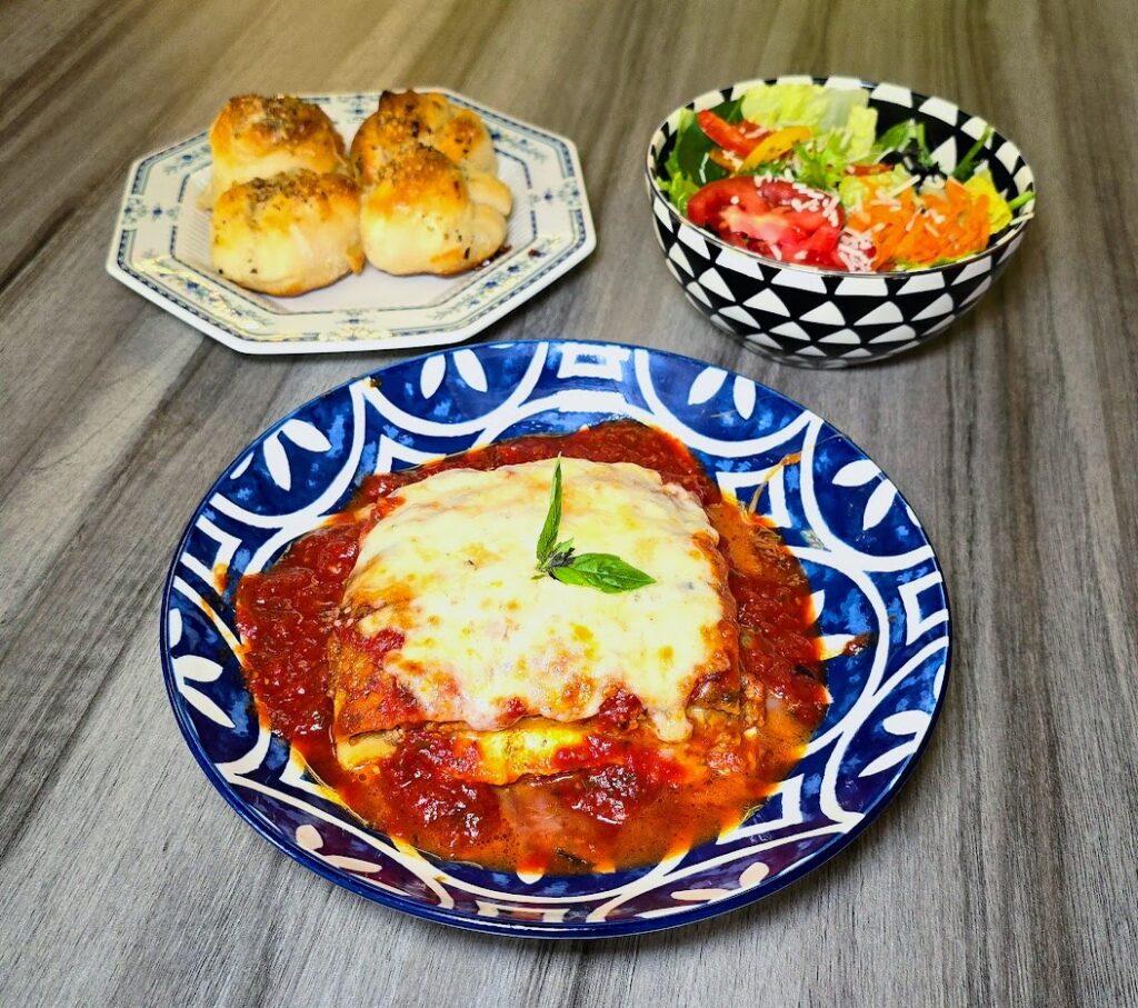 Lasagna dinner which includes a house salad and garlic knots as prepared by Giorgio's New York Pizzeria located in Vero Beach Florida