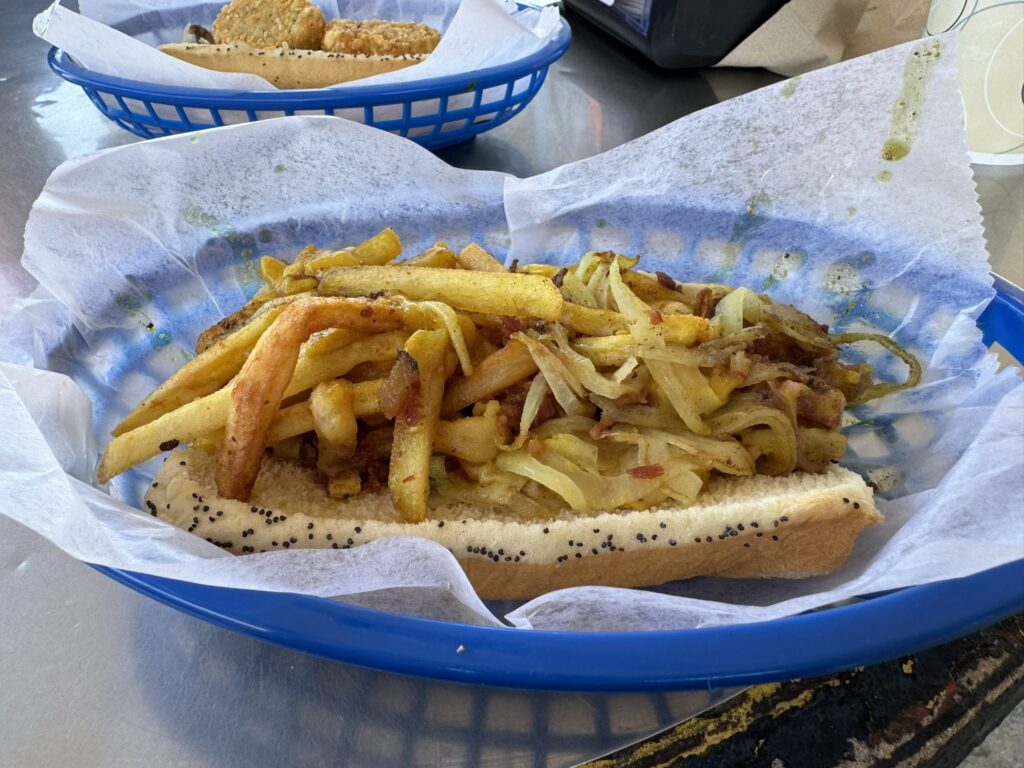 The Warrior Dog: Grilled hot dog, grilled onions, curried garlic mayo, bacon and topped with fries as prepared by Mustard's Last Stand in Melbourne, Florida