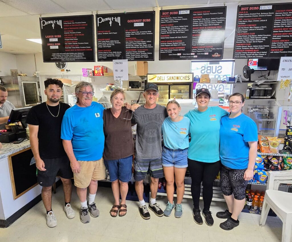 Previous owners and the new owners, along with a few employees at Penny Hill Subs in Vero Beach, Florida